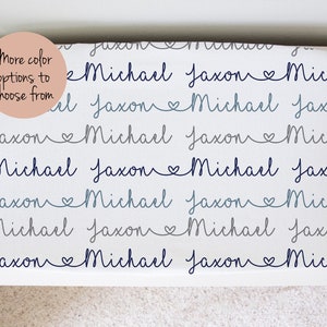 May include: White fabric with the names Michael and Jaxon repeated in a blue and gray script with a heart symbol between the names.