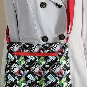 May include: A red and white crossbody bag with a black and white Star Wars print featuring the text "Star Wars" repeated throughout the design.