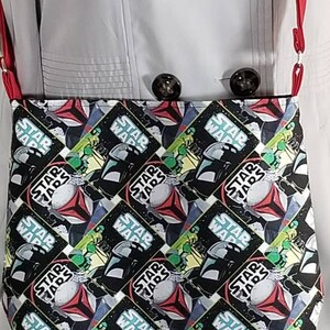 May include: A black and white Star Wars themed fabric tote bag with a red strap. The bag features a repeating pattern of Star Wars characters and the words "Star Wars".