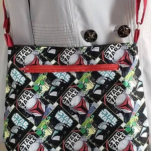 May include: A red and black crossbody bag with a Star Wars print. The bag has a zipper closure and a red strap.