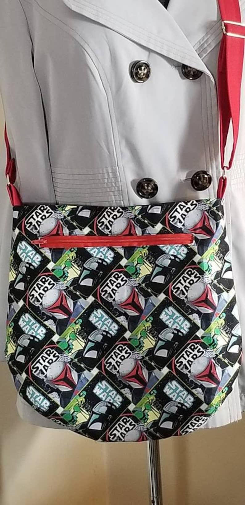 May include: A red and black crossbody bag with a Star Wars print. The bag has a zipper closure and a red strap.