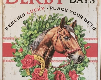 Puede incluir: Un letrero de metal de estilo vintage con fondo a rayas rojas y blancas. El letrero presenta un caballo marrón con una brida roja, una herradura y rosas rojas. El texto en el letrero dice "Derby Days", "Feeling Lucky", "Place Your Bets", "Crowd Favorite", "Roses", y "Run For The".