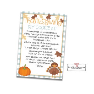 May include: A Thanksgiving DIY cookie kit instruction card with a blue and white checkered background. The card features a turkey and a pumpkin illustration. The text on the card reads "Thanksgiving DIY Cookie Kit".