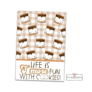 以下が含まれることがあります： チョコレートがトッピングされた漫画のマーシュマロウのパターンと、茶色と白の市松模様の背景を持つクッキーの印刷可能なデザイン。デザインの下部に「Life is s'more fun with cookies!」というテキストがあります。