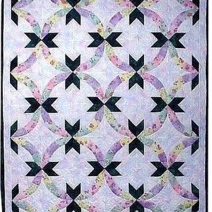 May include: A quilt with a repeating pattern of black stars and curved lines in shades of pink, purple, green, and yellow on a light purple background.