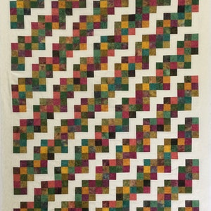 May include: A quilt with a diagonal pattern of colorful squares on a white background. The squares are in shades of green, brown, red, and yellow.