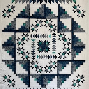May include: A square quilt with a geometric pattern in teal, navy, and grey on a white background. The design includes starbursts and repeating blocks. The quilt is machine-stitched, showcasing a detailed and symmetrical design.