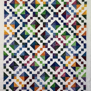 Puede incluir: Una colcha con fondo blanco y un patrón de formas de diamante de colores. Los diamantes están formados por cuadrados más pequeños en varios tonos de azul, verde, morado y naranja.