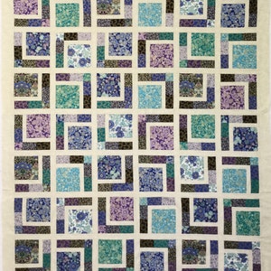 May include: A quilt with a patchwork design featuring a variety of floral patterns in shades of blue, purple, and green. The quilt is made up of squares and rectangles, and the fabric is sewn together in a grid pattern.