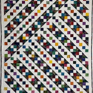 May include: A white quilt with a geometric pattern of colorful squares arranged in diagonal rows. The squares are set against a white background and are arranged in a staggered pattern.
