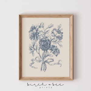 Puede incluir: Una impresi&oacute;n floral vintage azul y blanca con un ramo de rosas atado con una cinta. La impresi&oacute;n est&aacute; en un marco de madera.