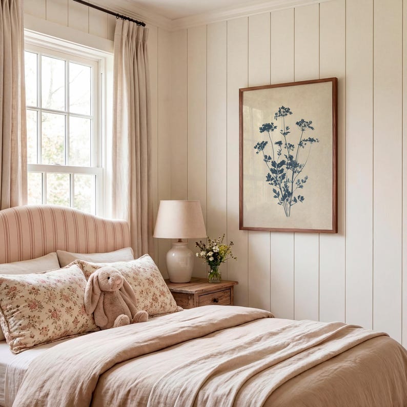 Puede incluir: Una pieza de arte mural rectangular que presenta una ilustraci&oacute;n bot&aacute;nica de flores silvestres en azul oscuro sobre un fondo beige claro, encerrada en un marco de madera simple, exhibida en una pared blanca con paneles verticales sobre una mesita de noche.