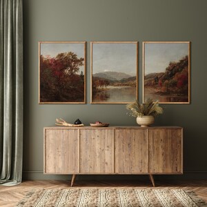 K&ouml;nnte beinhalten: Drei gerahmte Landschaftsbilder mit herbstlichen Szenen h&auml;ngen &uuml;ber einem Holzschr&auml;nkchen mit drei Schubladen. Die Bilder sind im rustikalen Stil gehalten und zeigen B&auml;ume, Berge und Fl&uuml;sse.