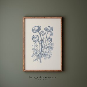 Puede incluir: Una impresi&oacute;n bot&aacute;nica azul y blanca de un ramo de flores en un marco sencillo. La impresi&oacute;n presenta un grupo de flores delicadas con detalles intrincados.