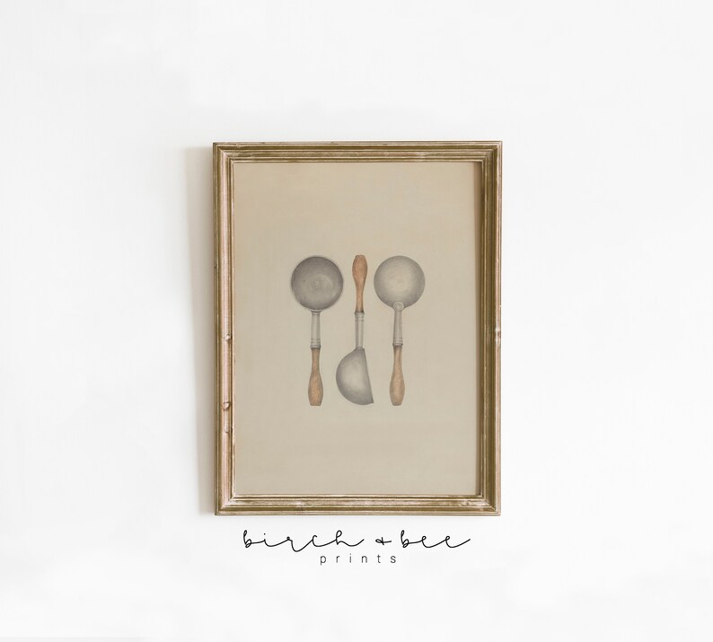 May include: A framed print of a watercolor illustration of three vintage kitchen ladles with wooden handles. The ladles are arranged vertically in a row. The background is a light beige color. The print is framed in a gold-colored frame.