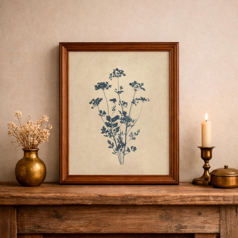 Puede incluir: Una l&aacute;mina de arte enmarcada que presenta una ilustraci&oacute;n bot&aacute;nica en azul oscuro de un grupo de flores silvestres centrada sobre un fondo beige claro. La obra est&aacute; encerrada en un marco de madera marr&oacute;n de tono medio y acabado liso.