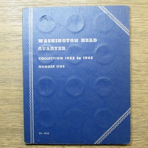 May include: A blue coin collection album with the text "WASHINGTON HEAD QUARTER COLLECTION 1932 to 1945 NUMBER ONE." The album has circular indentations for holding coins and a decorative white border.