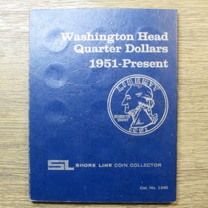 May include: A blue coin collecting album with the text "Washington Head Quarter Dollars 1951-Present." The album features a silver coin illustration with the word "LIBERTY" and the year "1951." The album also has the text "SHORE LINE COIN COLLECTOR."