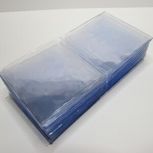 K&ouml;nnte beinhalten: Ein Stapel klarer, transparenter Plastikkartenh&uuml;llen. Die H&uuml;llen sind rechteckig und scheinen aus einem d&uuml;nnen, flexiblen Material zu bestehen. Der Stapel befindet sich auf einer transparenten Kunststoffbasis, der Hintergrund ist wei&szlig;.