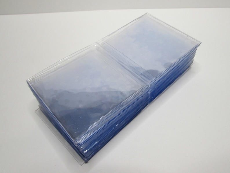 K&ouml;nnte beinhalten: Ein Stapel klarer, transparenter Plastikkartenh&uuml;llen. Die H&uuml;llen sind rechteckig und scheinen aus einem d&uuml;nnen, flexiblen Material zu bestehen. Der Stapel befindet sich auf einer transparenten Kunststoffbasis, der Hintergrund ist wei&szlig;.