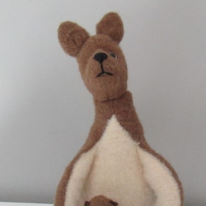 May include: A brown felt kangaroo with a cream-colored pouch holding a smaller brown felt joey. The kangaroo has black eyes and a black nose.