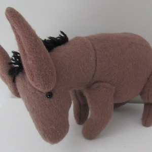 May include: A brown plush donkey toy with black yarn for its mane and tail. The donkey has large floppy ears and black button eyes.