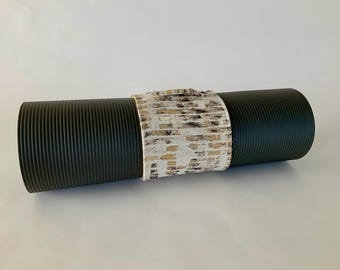 May include: A black yoga mat with a white and gold patterned fabric band around the center.