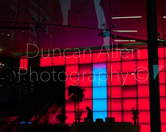 May include: A red and blue tiled wall with the text "Duncan Allen Photography ©" in white. A person stands in front of the wall, silhouetted against the bright lights.