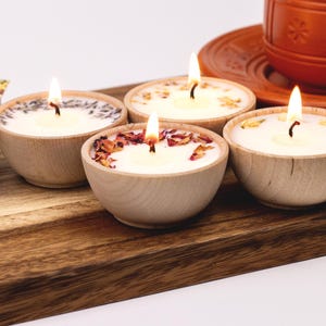 Set of four one ounce aromatherapy candles in a wooden cup reusable eco friendly sustainable pure soy and essential oil candle lavender eucalyptus orange grapefruit rosemary palmarosa essential oils and custom oil blends for calm gift relax spa gift Set of four essential oil soy tealight candles from Megan’s Pantry in reusable wooden bowls, adorned with botanicals—natural, eco-friendly aromatherapy gift set.