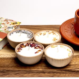 Set of four one ounce aromatherapy candles in a wooden cup reusable eco friendly sustainable pure soy and essential oil candle lavender eucalyptus orange grapefruit rosemary palmarosa essential oils and custom oil blends for calm gift relax spa gift Set of four essential oil soy tealight candles from Megan’s Pantry in reusable wooden bowls, adorned with botanicals—natural, eco-friendly aromatherapy gift set.