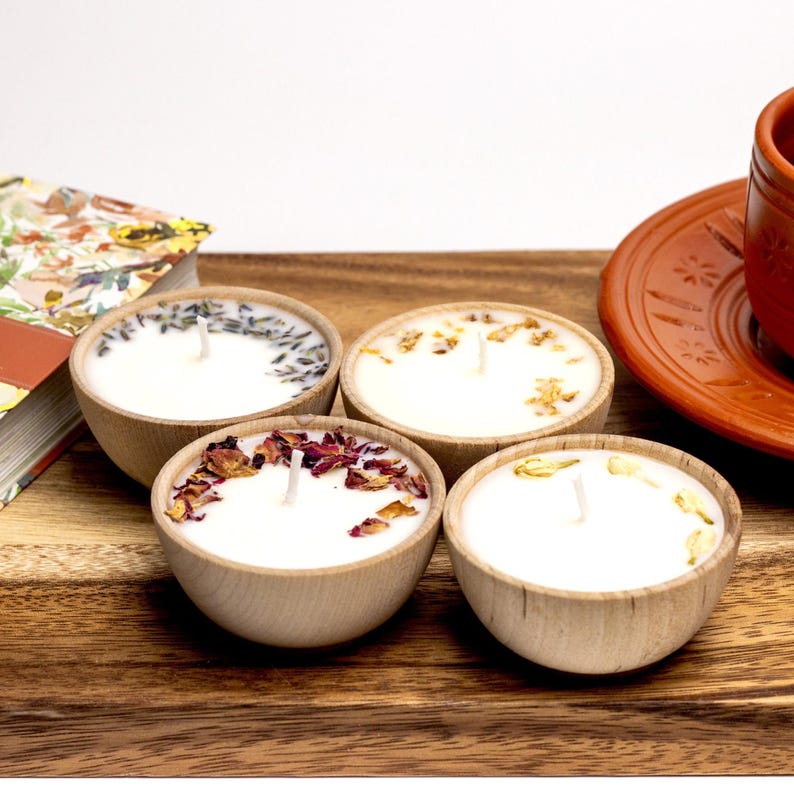 Set of four one ounce aromatherapy candles in a wooden cup reusable eco friendly sustainable pure soy and essential oil candle lavender eucalyptus orange grapefruit rosemary palmarosa essential oils and custom oil blends for calm gift relax spa gift Set of four essential oil soy tealight candles from Megan’s Pantry in reusable wooden bowls, adorned with botanicals—natural, eco-friendly aromatherapy gift set.