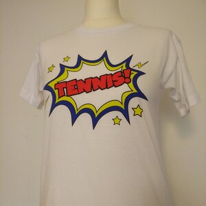 May include: White t-shirt with a red, yellow, and blue comic book style graphic that says "TENNIS!"