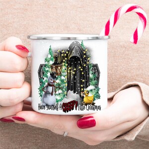 Op de afbeelding: Witte emaille mok met een zwarte gekapte figuur, een sneeuwpop, een gele rubberen eend en een kerstboom met lichtjes. De tekst luidt "Have Yourself A Creepy Little Christmas".