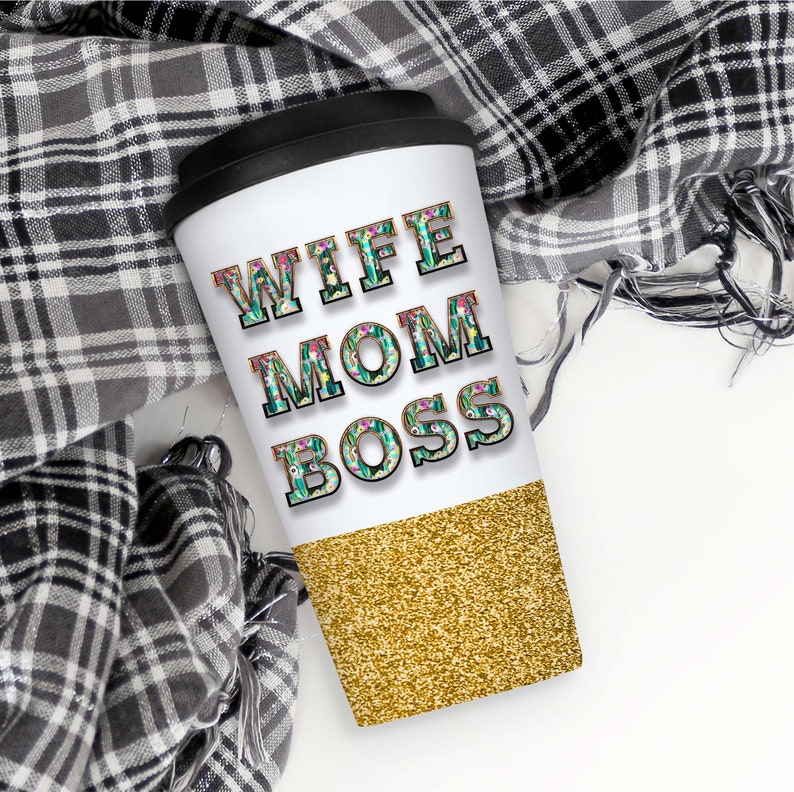 May include: White travel mug with a gold glitter bottom. The mug has the words "Wife Mom Boss" in black letters with a floral design.
