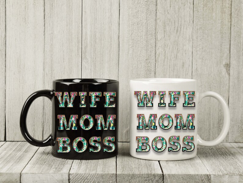 May include: Two coffee mugs with the text "Wife Mom Boss" in floral letters. One mug is black and the other is white.