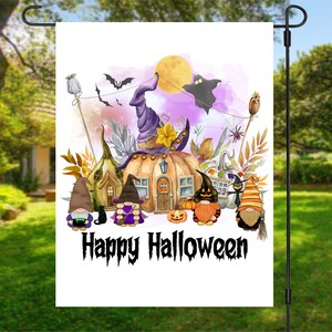 Pu&ograve; includere: Una bandiera da giardino bianca con un'illustrazione ad acquerello di una casa a forma di zucca sormontata da un cappello da strega. Davanti alla casa ci sono gnomi, un gatto nero e un fantasma. Il testo "Happy Halloween" &egrave; scritto in nero nella parte inferiore della bandiera.
