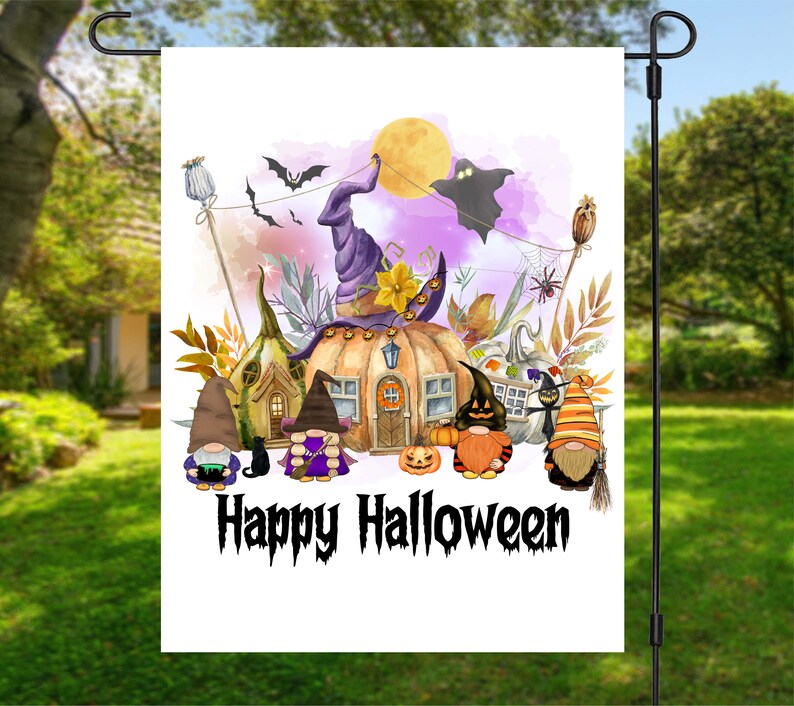 Pu&ograve; includere: Una bandiera da giardino bianca con un'illustrazione ad acquerello di una casa a forma di zucca sormontata da un cappello da strega. Davanti alla casa ci sono gnomi, un gatto nero e un fantasma. Il testo "Happy Halloween" &egrave; scritto in nero nella parte inferiore della bandiera.