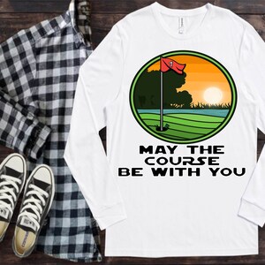May include: White long-sleeved t-shirt with a green, yellow and red golf course graphic and the text "May the course be with you".