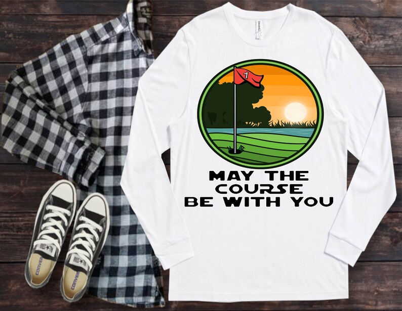 May include: White long-sleeved t-shirt with a green, yellow and red golf course graphic and the text "May the course be with you".
