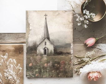 May include: An artistic composition featuring a church painting with a tall steeple, a white envelope, and wooden elements. The painting depicts a church in a field of flowers. Decorative flowers and a gold bowl add to the aesthetic.