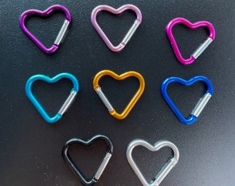 May include: Nine heart-shaped metal keychains in different colors, including purple, pink, blue, gold, and black.