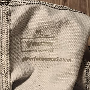 May include: White athletic wear with black trim and a label that reads "M Performance System" and "VingCard Engineered Innovations".
