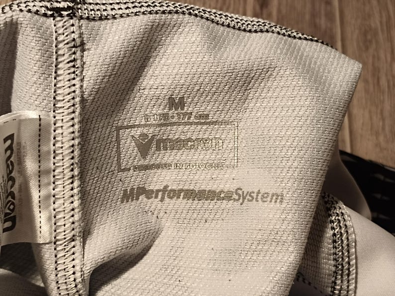 May include: White athletic wear with black trim and a label that reads "M Performance System" and "VingCard Engineered Innovations".