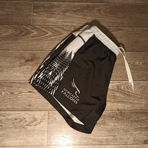 May include: Black and white athletic shorts with a white and black geometric pattern and the words "NEWCASTLE FALCONS" in white text.