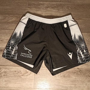 May include: Black and white athletic shorts with a black and white graphic pattern. The shorts have the text "NEWCASTLE FALCONS" on the left leg.