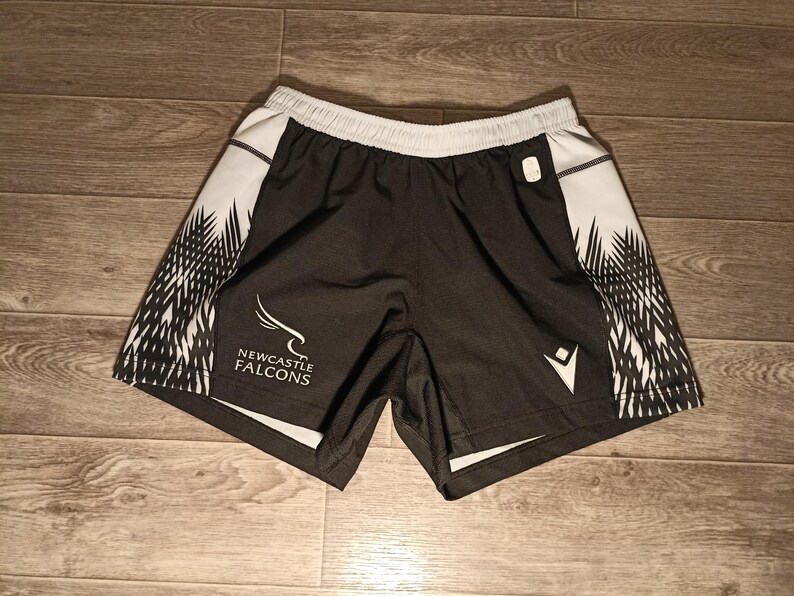 May include: Black and white athletic shorts with a black and white graphic pattern. The shorts have the text "NEWCASTLE FALCONS" on the left leg.