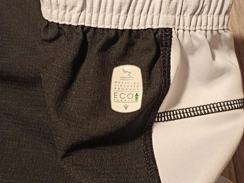 May include: Black and white athletic shorts with a white waistband and a black label that says "New Era Authentic Official Licensed Product ECO Fabric".