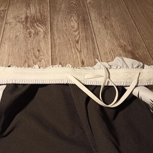 May include: Black and white athletic shorts with a white drawstring. The shorts have a geometric pattern.