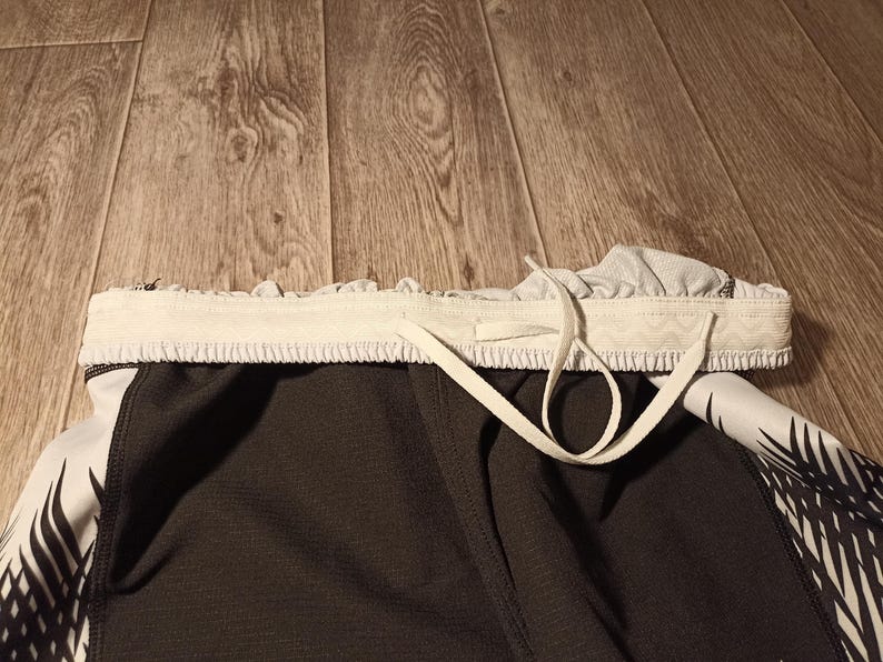 May include: Black and white athletic shorts with a white drawstring. The shorts have a geometric pattern.