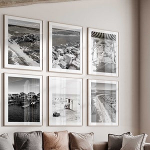May include: A living room with a sectional sofa, a coffee table, and an armchair. The walls are decorated with black and white photographs of a coastal town.
